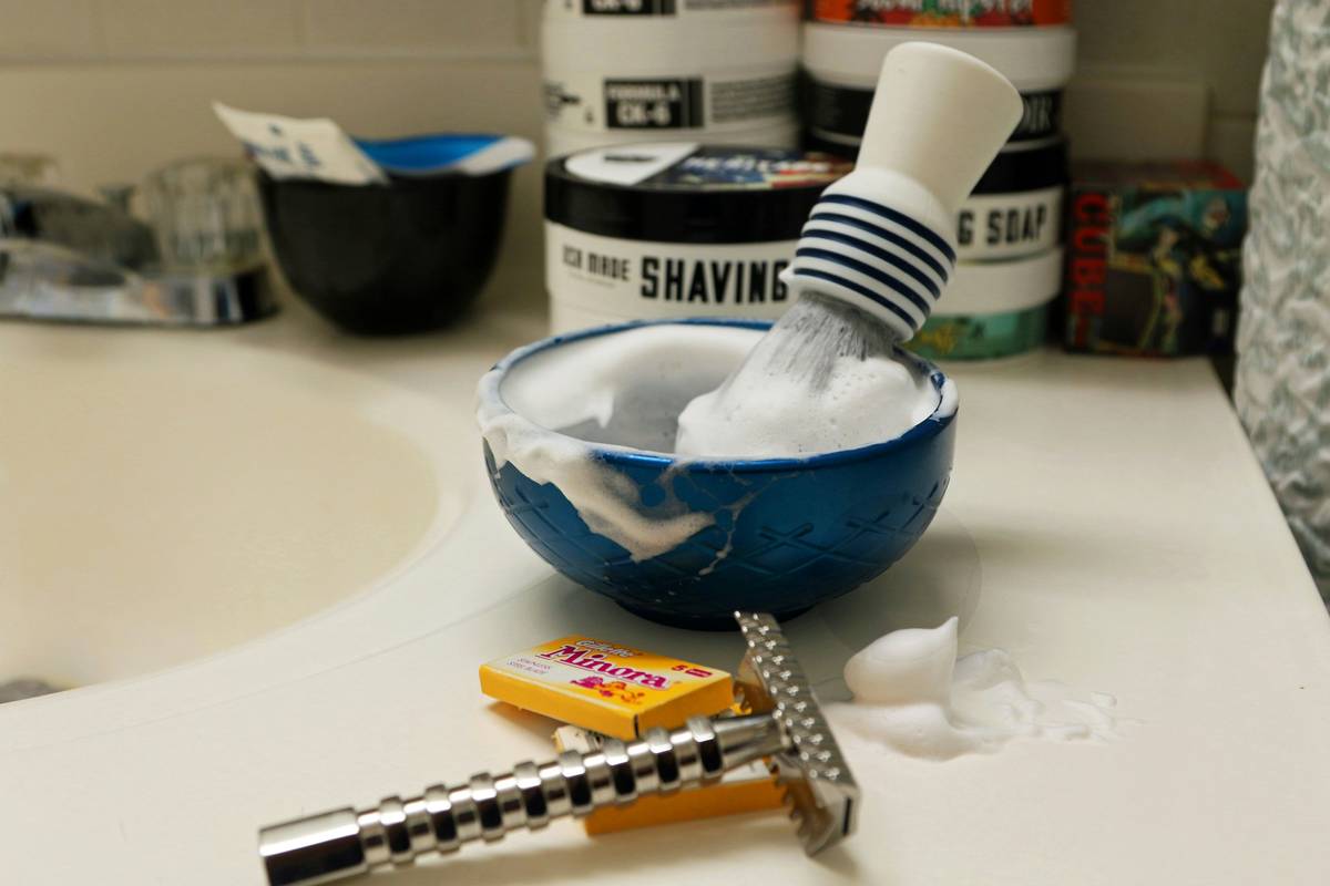 Close-up of creamy shaving soaps with rich lather being whipped in a shaving bowl using a badger brush