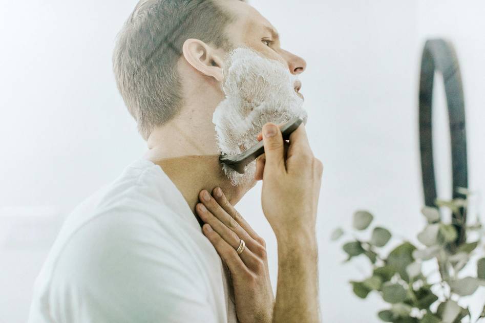 Vintage-style shaving setup with handmade shaving soap puck, badger brush, and lather bowl on wooden surface